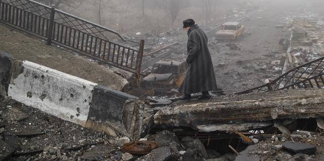 An elderly woman walks across a destroyed bridge, fallen onto the road towards the airport, the scene of heavy fighting in Donetsk, Ukraine, Sunday, March 1, 2015.  The recent pullback of some weapons from the line separating government and rebel forces in Ukraine seems to have boosted the prospects for peace, although both sides are warning of their readiness to resume fighting if necessary. (ANSA/AP Photo/Vadim Ghirda)